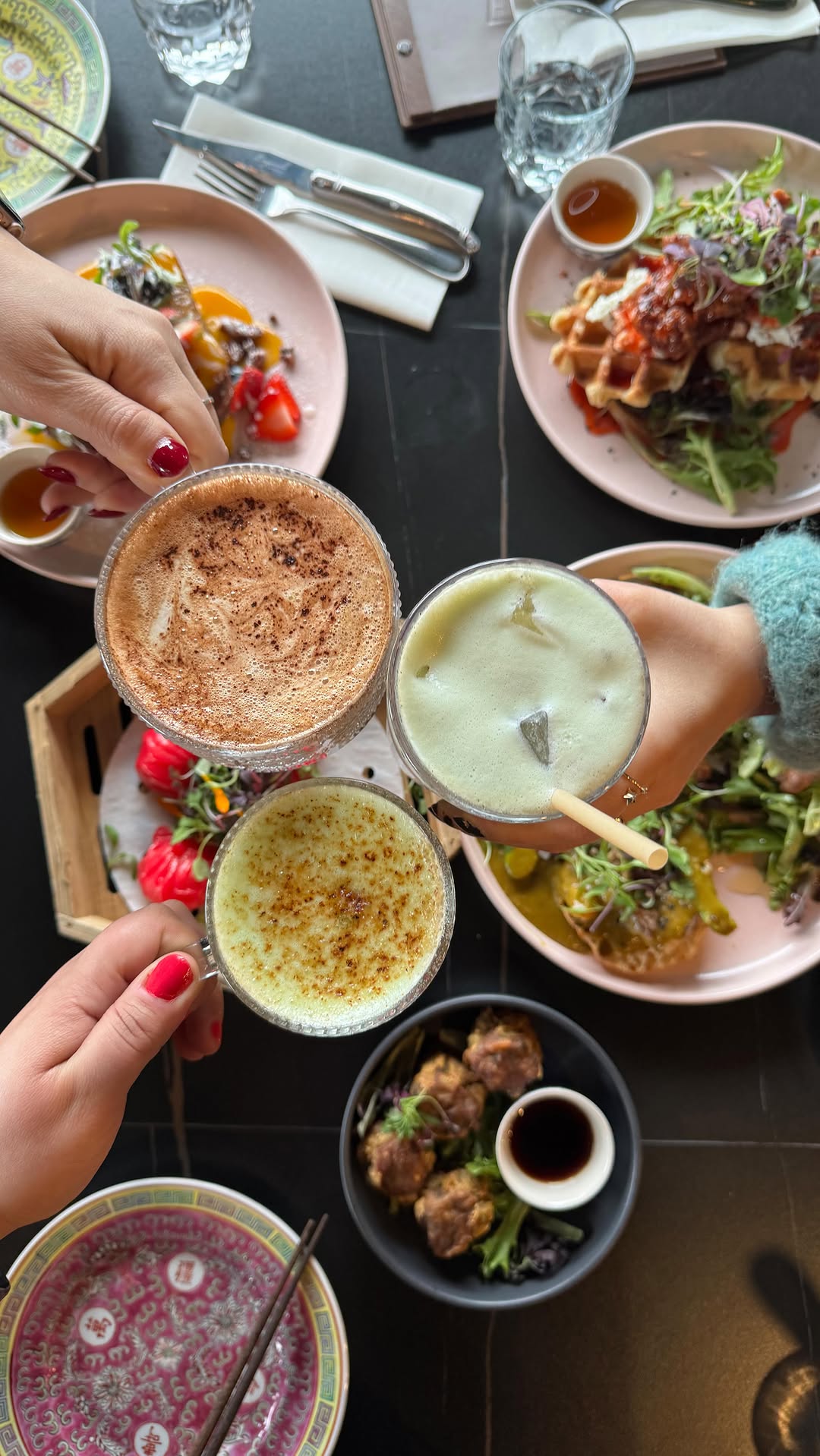 Amis trinquant avec des lattés au-dessus d'une table de brunch